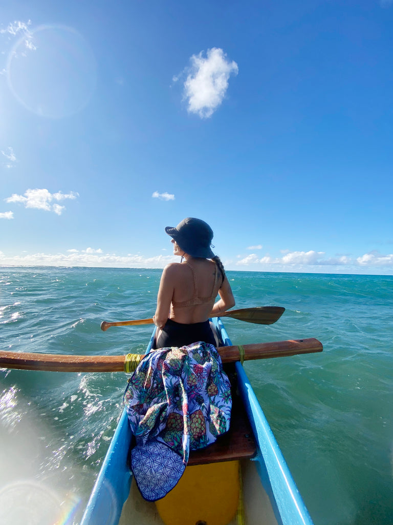 Pineapple Surfer Towel draped over an outrigger canoe in the ocean